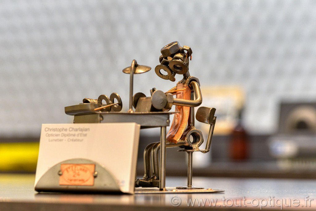 petite sculpture porte-carte, représentant un petit homme fabricant des lunettes. Il est fait de vis, de clous et de boulons, assis sur une chaise