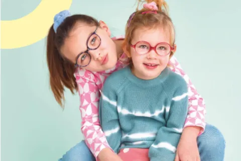lunettes pour enfants deux jeunes filles portant des lunettes. elles sont assises et sourient. c'est une photo produite par OptiKid, opticien Nanterre ville